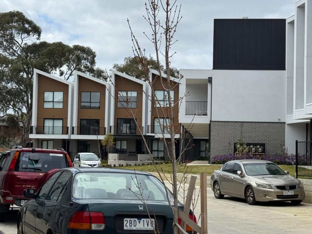 Street view of townhouses with light rendered walls and brick facade details