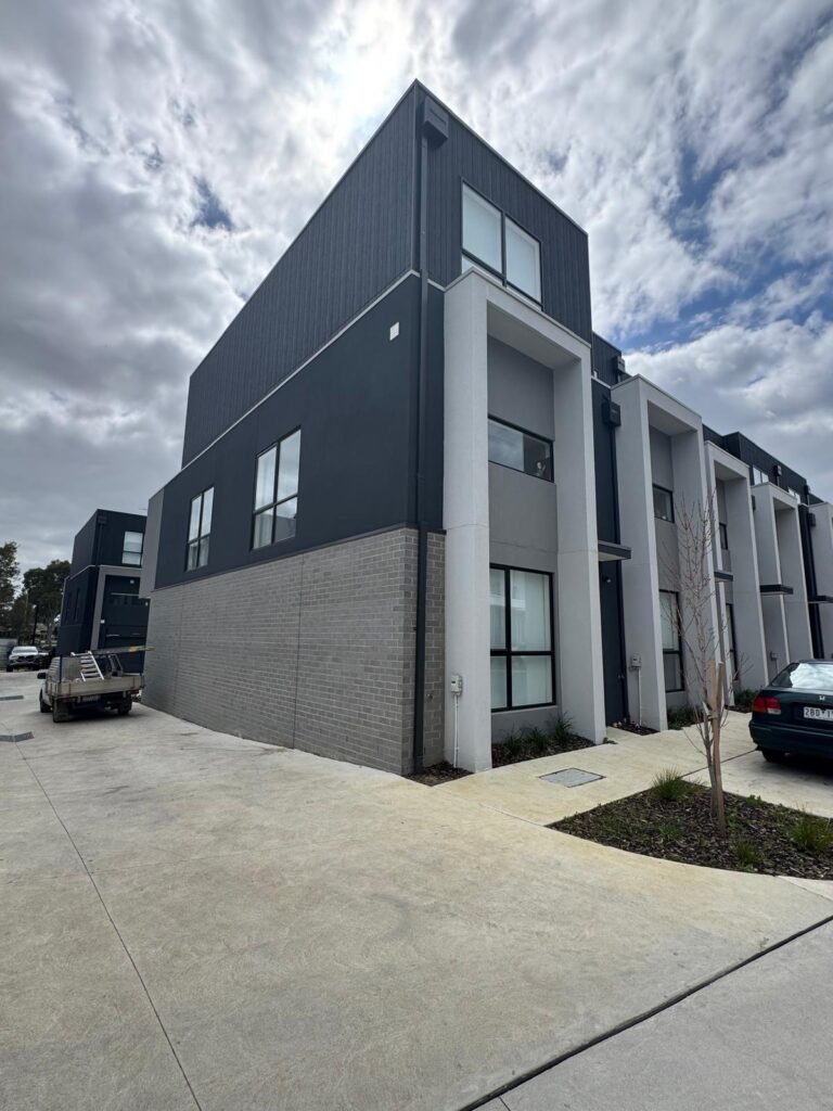 Dark upper cladding above light rendered townhouse walls
