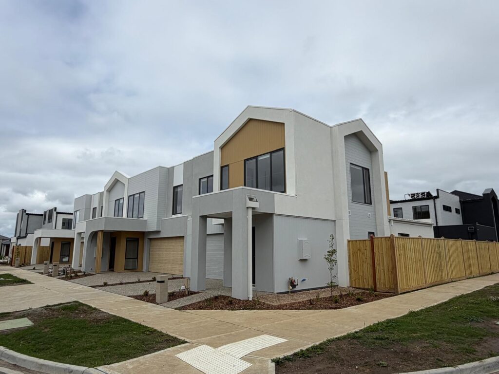 Townhouse corner with light render and warm-toned facade panels